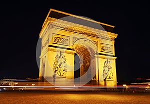 Traffic goes around the Arc De Triomphe at night