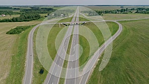 Traffic interchange four-lane motorway. Trucks ride along road junking. Aerial