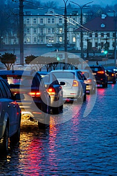 Traffic jam in the city at night during the rain. Rear view of cars standing on the road and red headlights. Reflection of red car