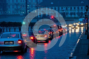 Traffic jam in the city at night during the rain. Rear view of cars standing on the road and red headlights. Reflection of red car