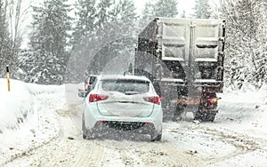 Traffic jam on forest road, cars and trucks moving slowly - mountain pass during heavy snow blizzard