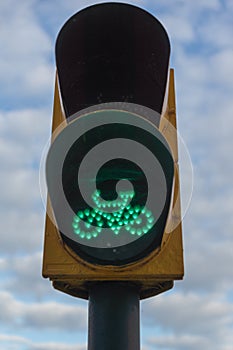 Traffic light for bicycles in green over cloudy blue sky