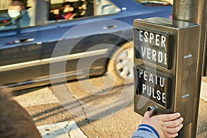 A child presses a button on a traffic light to activate the green phase and be able to safely cross the street