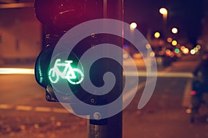 Traffic light for a cycling lane showing green bicycle symbol in colorful night scene