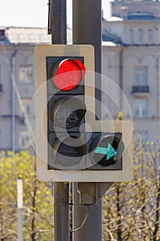 Traffic light with forbidding red signal and permissive green signal of right arrow section on city street in sunny day closeup photo