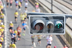 Traffic light in the foreground - people running a half marathon on the bridge