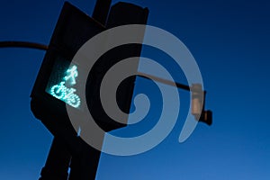 Traffic light in green for pedestrians and cyclists, with the figure of a cyclist. Night background for the concept of freeway and