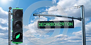 Traffic light with leaf symbol and road information board with text DECARBONIZATION photo