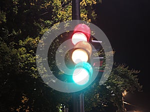 Traffic light at night-time showing red, yellow, and green