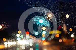traffic light with red arrow in storm and dark rain clouds defocused as light symbols seen from car windshield, USA