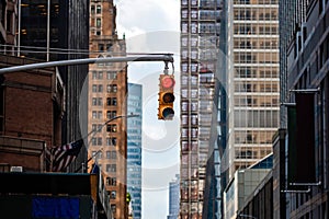 Traffic light with red light above Manhatan street among many skyscrapers