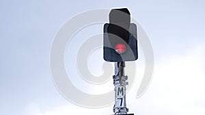 Traffic light shows red signal on railway on a gray background