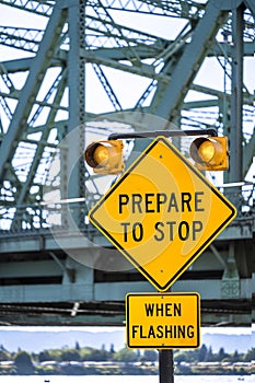 Traffic light warning signal with traffic sign prepare to stop on the access road to the truss drawbridge over the river