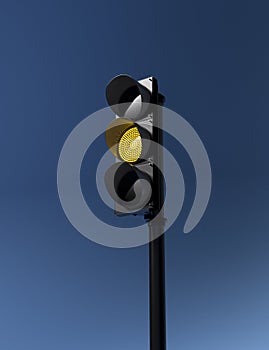 Traffic light with working yellow signal isolated on blue sky background