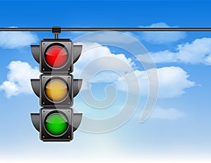 Traffic lights with all three colors on hanging against blue sky