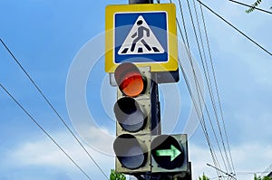 Traffic lights over urban intersection. Red light and green arrow. Pedestrian crossing sign