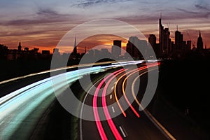 Traffic with motion cars with luminous lines of speed and the evening European city of Frankfurt with beautiful sunset sky,