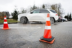 Traffic orange cones standing on a street along the parking cars