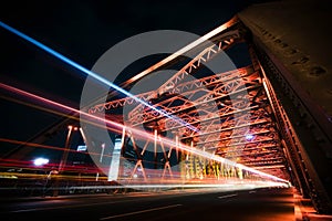 Traffic on red steel bridge at night