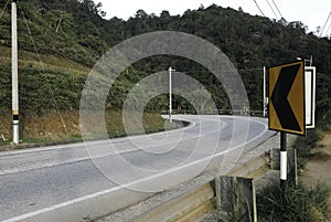 Traffic road sign warning a sharp bend in front on an empty street