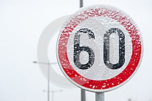 Traffic road speed limit 60 sign on the street covered with snow in danger slippery winter season close up