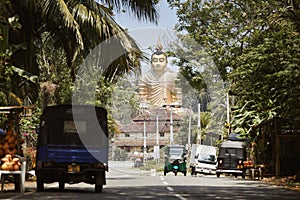 Traffic on rural road against Buddha statue in Sri Lanka