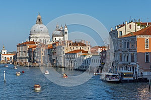 Traffic rush on Grand Canal with boats, gondolas and Venetian vaporetto. Basilica Santa Maria della Salute in the background