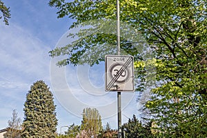 Traffic sign: 30 km zone ends, trees with lush green foliage and a blue sky in the background