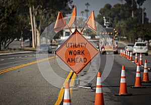 Traffic sign with flags reading Utilitary Work Ahead with traffic cones on road with electronic arrow pointing to the right photo