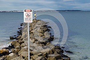 Traffic sign for High risk activity , avoid rocky coastal ocean wall.