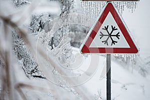 Traffic sign for icy road with sleet covered trees