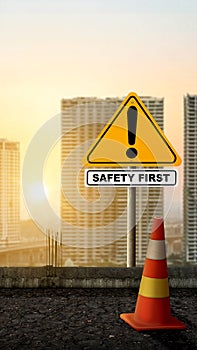 A traffic sign with \'safety first\' text and a traffic cone