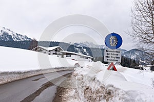 Snow chain obligation, Chain traffic sign. Winter time and winter services. Snow covered road, trees. Austria