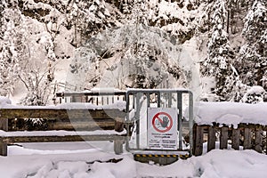 No entry, Power station - Warning sign hung on a metal gate. Snow-covered trees and a wooden fence around