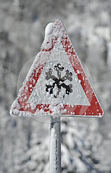 Traffic sign warns of snow and ice at winter on road