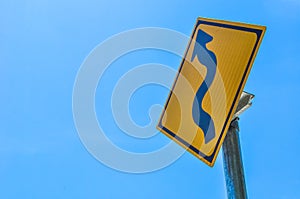 Traffic sign winding road on blue sky background