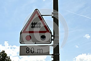 Traffic signs arrange vertical are meaning railroad crossing ahead with barrier with traffic light in distance of 80 metres.