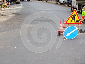 Traffic signs and stacked traffic cones stand on the road where repair work is underway