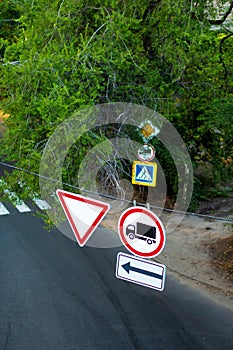 Traffic signs on a wire over the road. A sign obliging to give way. And forbidding the passage of trucks photo