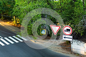 Traffic signs on a wire over the road. A sign obliging to give way. And forbidding the passage of trucks