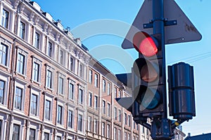 A traffic stop light is on red with typical Danish buildings in