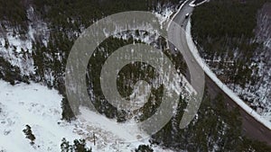 Traffic on a winter day. Cars on road in winter with snow covered trees aerial view.