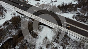 Traffic on a winter day. Cars on road in winter with snow covered trees aerial view.