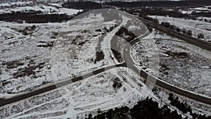 Traffic on a winter day. Cars on road in winter with snow covered trees aerial view.