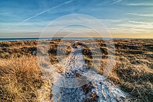 A trail on a beach leads to a calm sea amid tranquility conveying the idea of a life journey, mission and achievement concepts