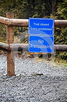 Trail closed. Entry prohibited. No trespassing. Sign posted on a fence to prevent the passage of persons and vehicles. Natural