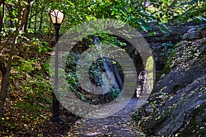 Trail with lamppost and stone tunnel in Central Park woods New York City