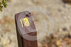 Trail Mile Marker Number Eighteen (18) carved on a wooden post and painted yellow