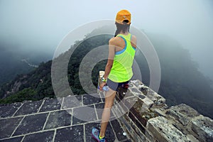 Trail runner haves a rest at great wall on the top of mountain