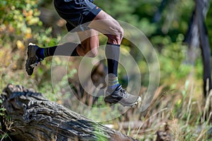 trail runner midjump over log, compression socks evident
